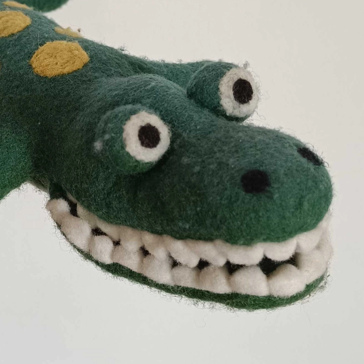 A crocodile plush with yellow spots on his back. He has big bulbous eyes.